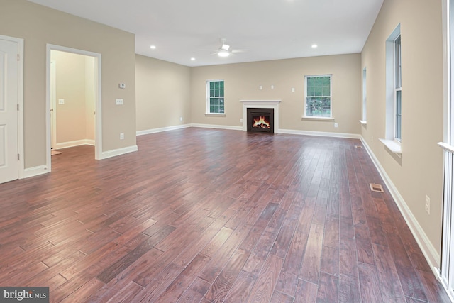 unfurnished living room featuring a wealth of natural light, dark hardwood / wood-style floors, and ceiling fan