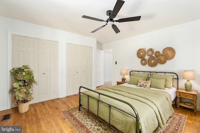 bedroom with hardwood / wood-style floors, ceiling fan, and multiple closets