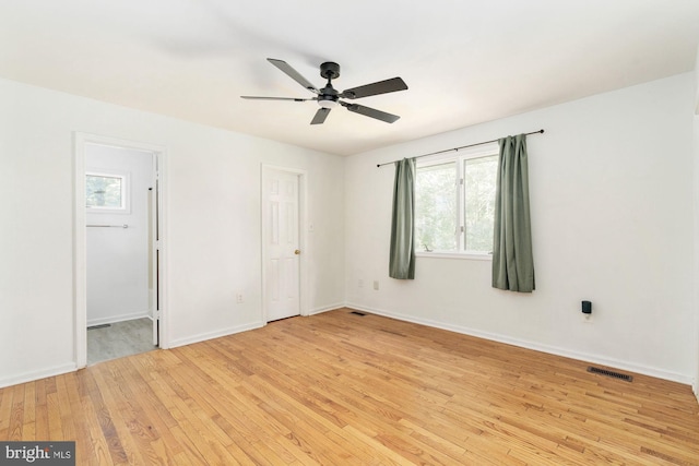 empty room featuring a healthy amount of sunlight, ceiling fan, and light hardwood / wood-style floors