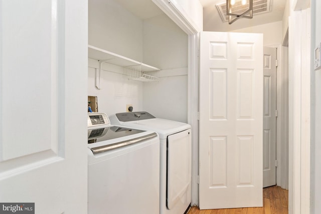 laundry room with separate washer and dryer and light hardwood / wood-style flooring