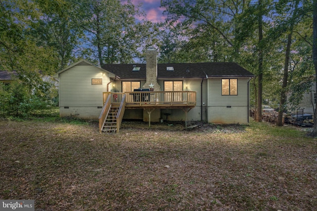 back house at dusk featuring a deck