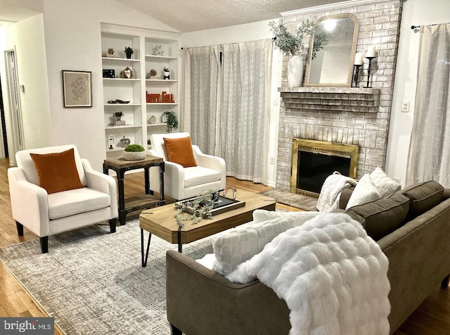 living area featuring vaulted ceiling, a fireplace, a textured ceiling, and hardwood / wood-style flooring