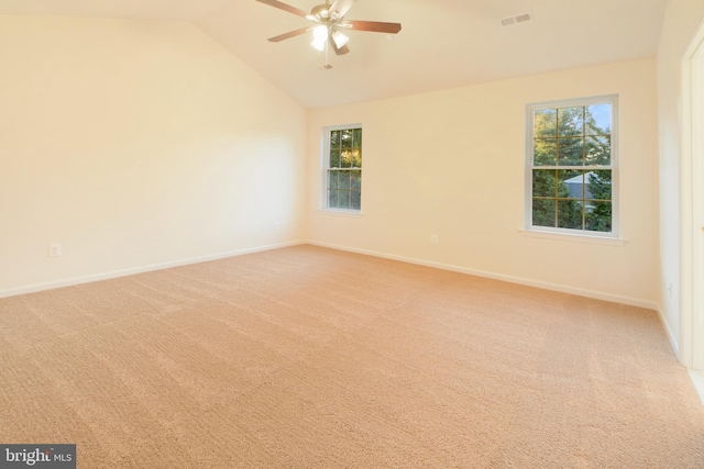 carpeted empty room with a wealth of natural light, ceiling fan, and vaulted ceiling