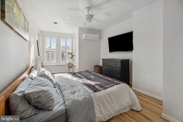 bedroom featuring ceiling fan, light hardwood / wood-style floors, and a wall mounted AC