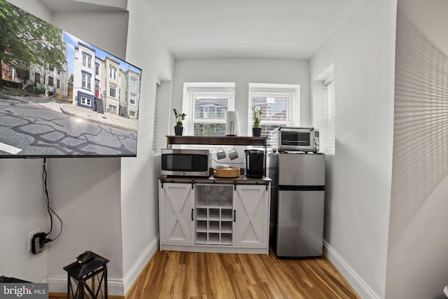 bar featuring hardwood / wood-style floors and appliances with stainless steel finishes