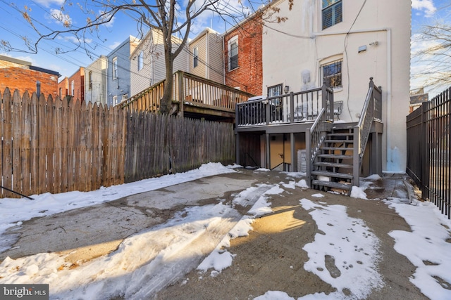 snow covered house featuring a wooden deck