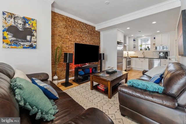 living room featuring light wood-type flooring, ornamental molding, sink, and brick wall