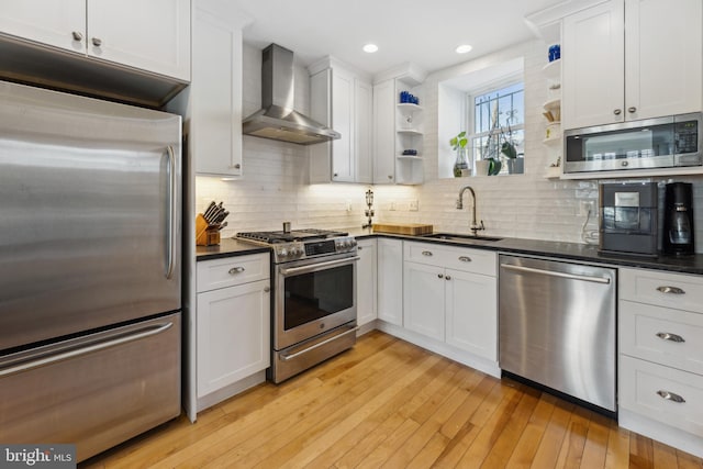 kitchen with white cabinetry, sink, stainless steel appliances, and wall chimney range hood