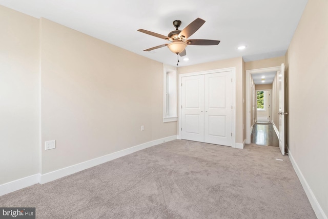 unfurnished bedroom with ceiling fan, a closet, and light colored carpet