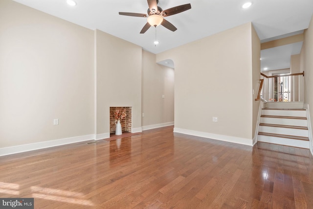 unfurnished living room featuring ceiling fan, wood-type flooring, and a fireplace