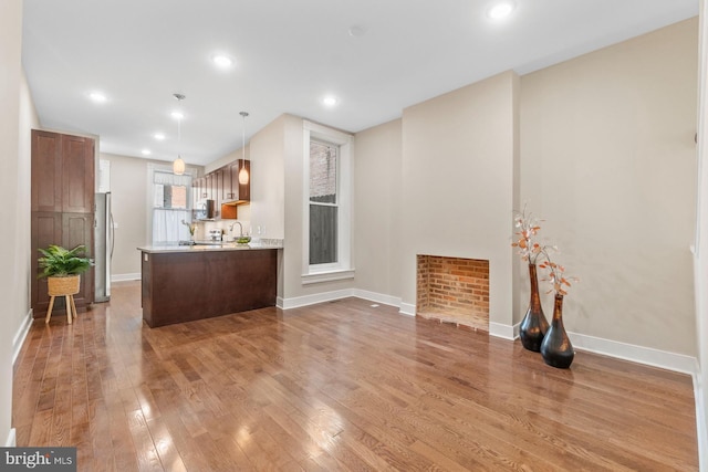 kitchen with pendant lighting, hardwood / wood-style floors, sink, kitchen peninsula, and stainless steel appliances