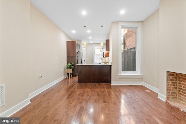 interior space featuring decorative light fixtures, stainless steel refrigerator, hardwood / wood-style flooring, and sink