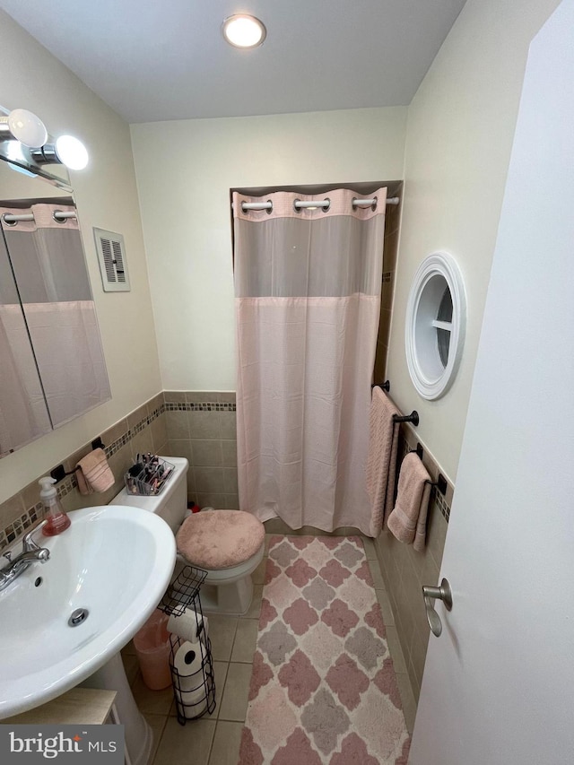 bathroom with sink, tile patterned flooring, tile walls, a shower with shower curtain, and toilet