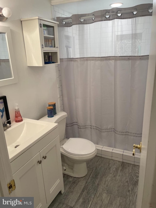 bathroom with wood-type flooring, toilet, a shower with shower curtain, and vanity