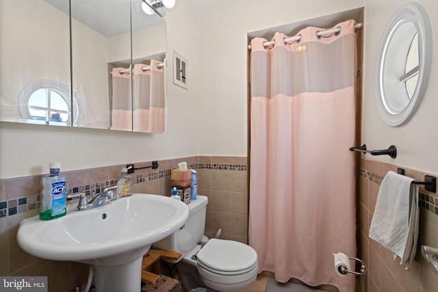 bathroom featuring toilet, sink, tile walls, and walk in shower