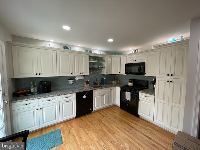 kitchen featuring white cabinetry, light hardwood / wood-style floors, sink, and black appliances