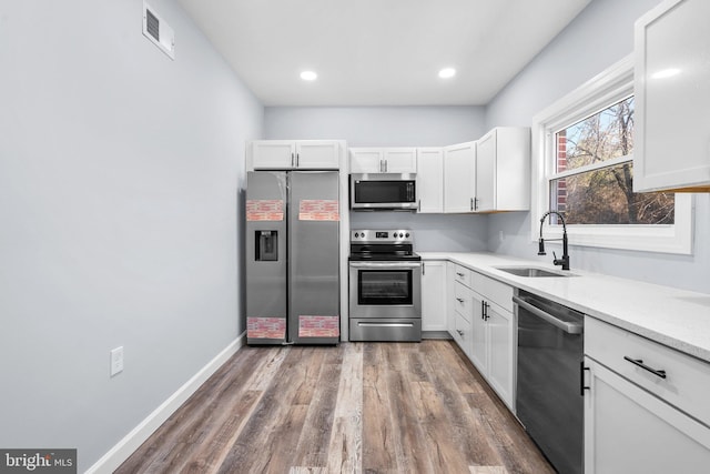 kitchen with dark hardwood / wood-style flooring, sink, white cabinets, and appliances with stainless steel finishes