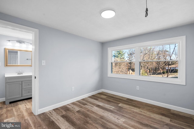 unfurnished bedroom featuring hardwood / wood-style floors, sink, and connected bathroom