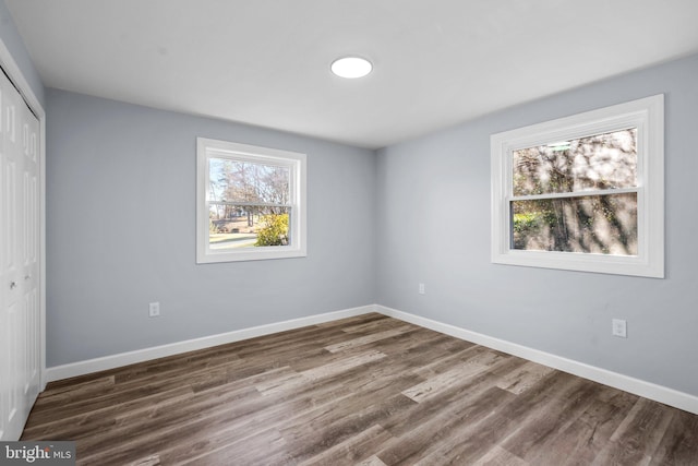 unfurnished bedroom featuring multiple windows, a closet, and dark wood-type flooring