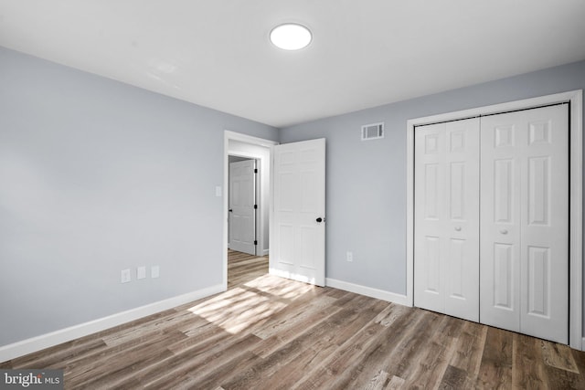 unfurnished bedroom with hardwood / wood-style flooring and a closet