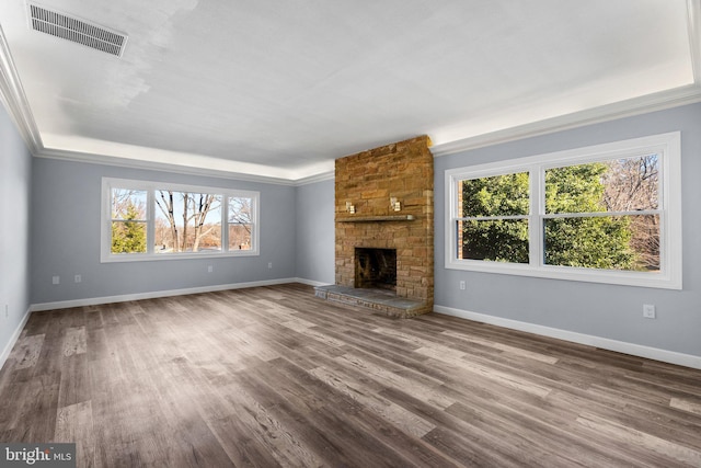 unfurnished living room with a stone fireplace, wood-type flooring, and crown molding