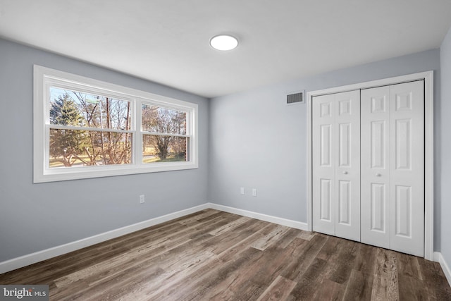 unfurnished bedroom featuring a closet and dark hardwood / wood-style floors