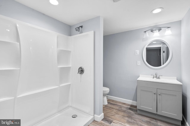 bathroom with a shower, vanity, hardwood / wood-style flooring, and toilet