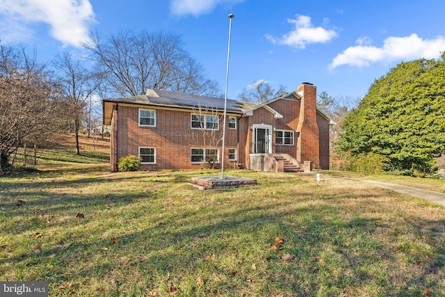 back of property with a yard and solar panels