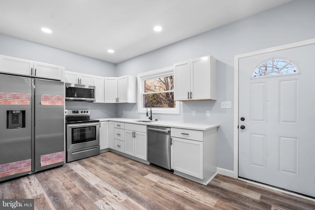 kitchen featuring white cabinets, light wood-type flooring, stainless steel appliances, and sink