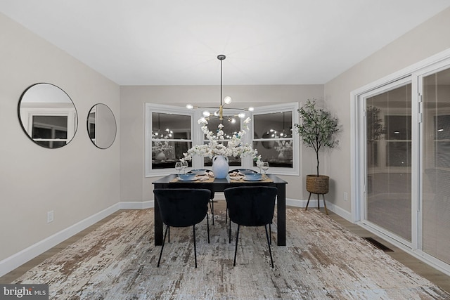 dining space with wood-type flooring and an inviting chandelier