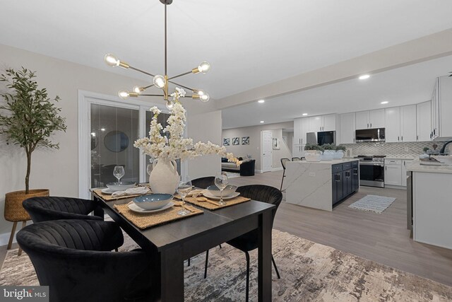 dining area featuring light hardwood / wood-style floors, a notable chandelier, and sink