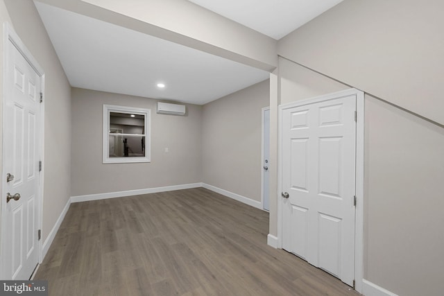 basement with a wall mounted air conditioner and light hardwood / wood-style flooring