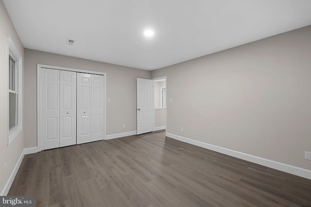 unfurnished bedroom featuring dark hardwood / wood-style floors and a closet