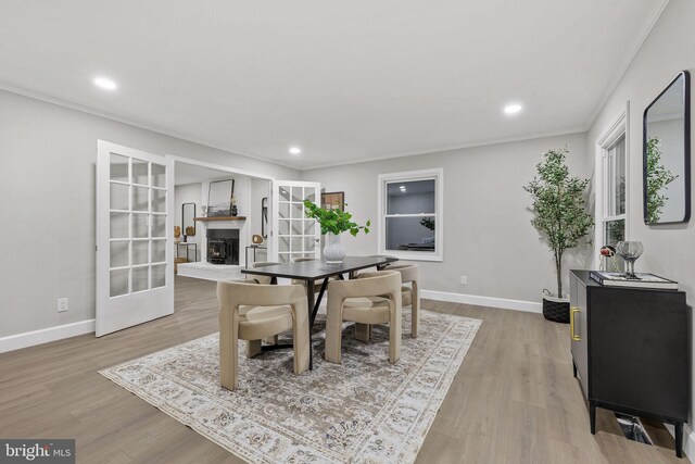 dining space featuring crown molding, light hardwood / wood-style flooring, and french doors