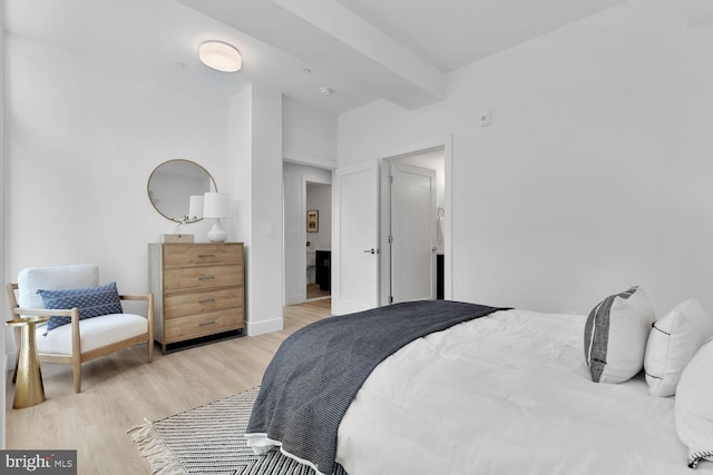 bedroom featuring beamed ceiling and light hardwood / wood-style flooring