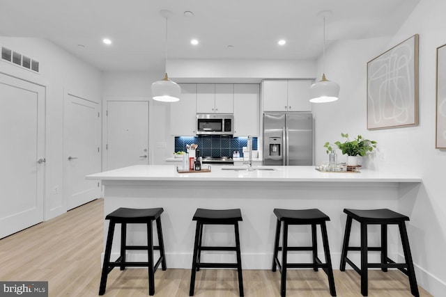 kitchen featuring white cabinets, pendant lighting, stainless steel appliances, and sink