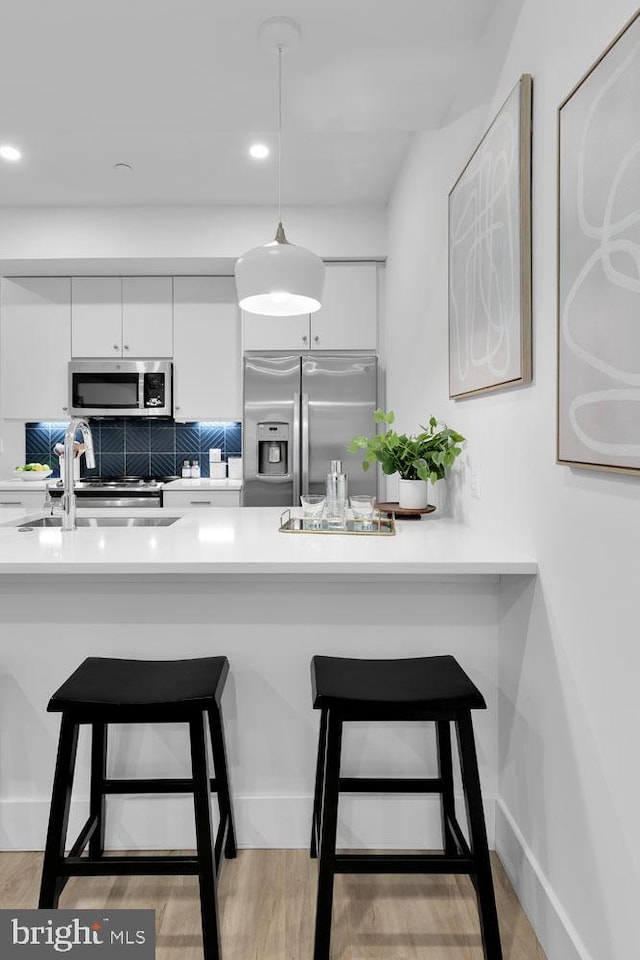 kitchen with a kitchen bar, sink, white cabinets, and stainless steel appliances