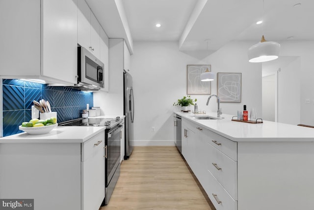 kitchen with kitchen peninsula, tasteful backsplash, stainless steel appliances, sink, and white cabinetry