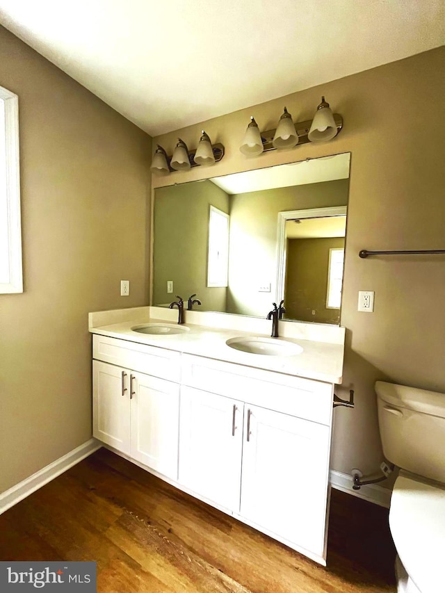 bathroom with wood-type flooring, vanity, and toilet