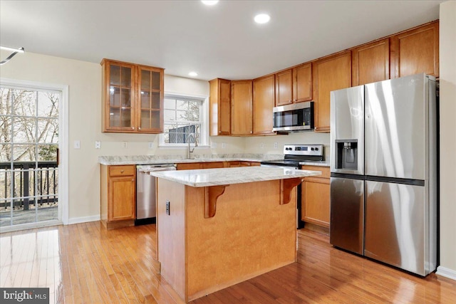 kitchen with a kitchen bar, appliances with stainless steel finishes, light hardwood / wood-style floors, a kitchen island, and plenty of natural light