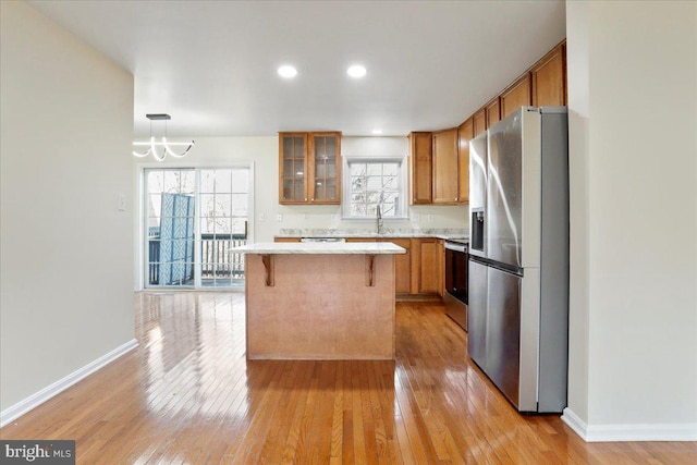 kitchen with a center island, range, decorative light fixtures, stainless steel fridge with ice dispenser, and a breakfast bar area