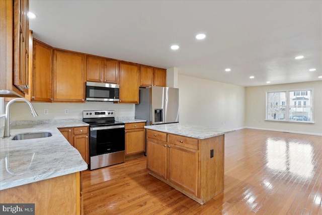 kitchen with a kitchen island, light stone countertops, sink, and appliances with stainless steel finishes