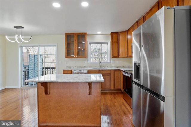 kitchen with hardwood / wood-style floors, decorative light fixtures, a center island, and stainless steel appliances