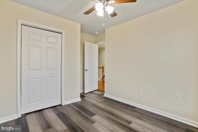 unfurnished bedroom with ceiling fan, dark wood-type flooring, and a closet