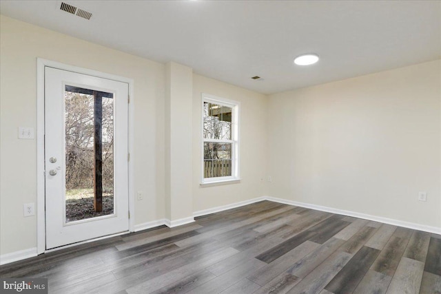 spare room featuring dark hardwood / wood-style floors and a healthy amount of sunlight