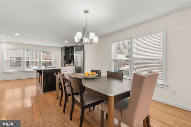 dining area with sink, light hardwood / wood-style flooring, and a chandelier