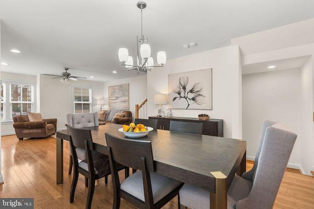 dining room with ceiling fan with notable chandelier and light wood-type flooring