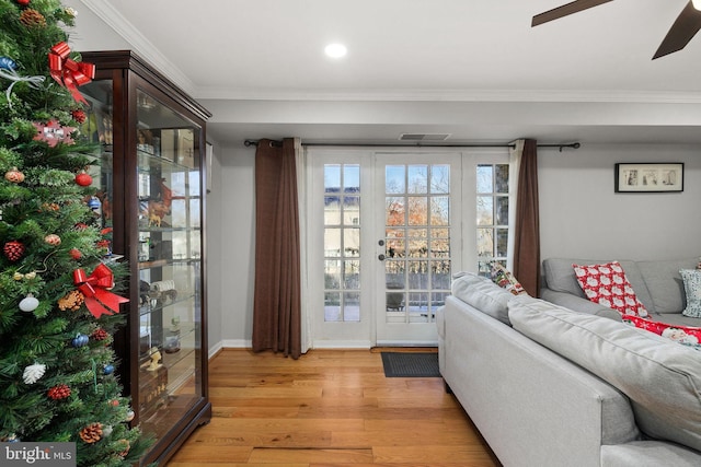 living room featuring crown molding, ceiling fan, and light wood-type flooring