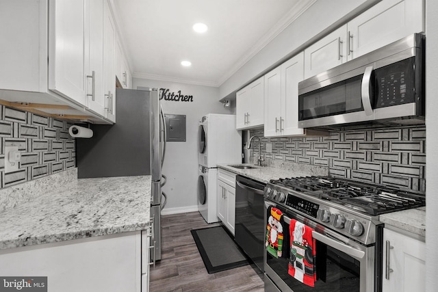 kitchen with stacked washing maching and dryer, stainless steel appliances, white cabinetry, and sink