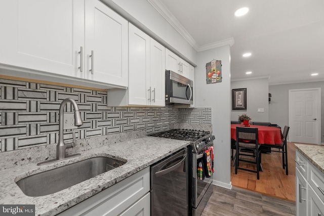 kitchen featuring light stone countertops, stainless steel appliances, crown molding, sink, and white cabinetry